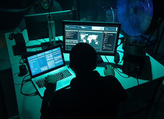 Shadowed figure working on Laptop and desktop