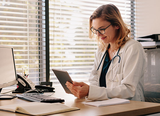 Women in lap coat looking at tablet