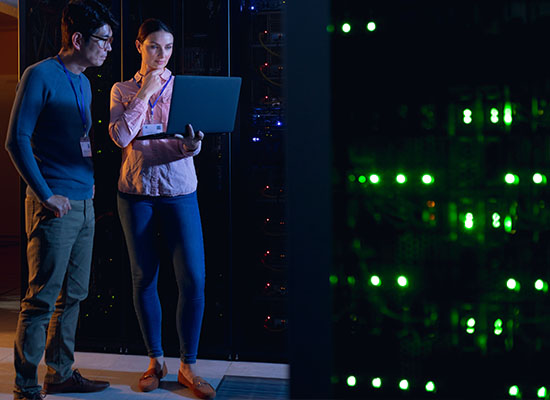 Man and women looking at laptop while in computer server room