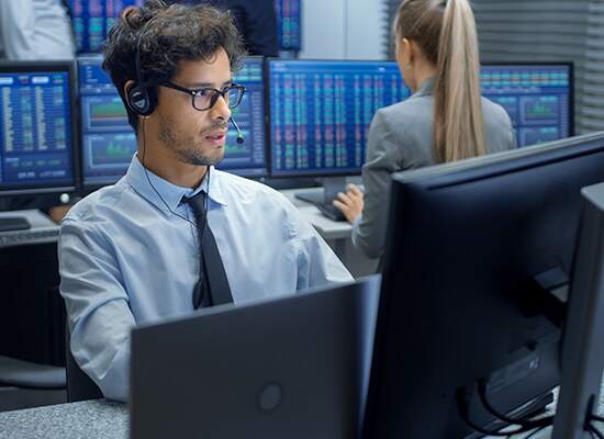 Man working looking at desktop and laptop