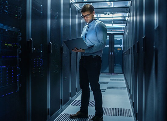 Man on laptop looking at computer servers