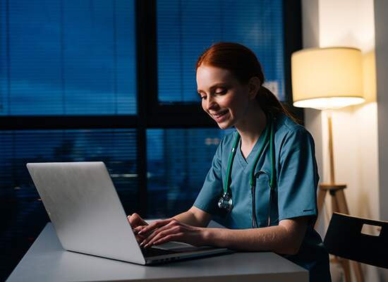 Women in scrubs typing on laptop
