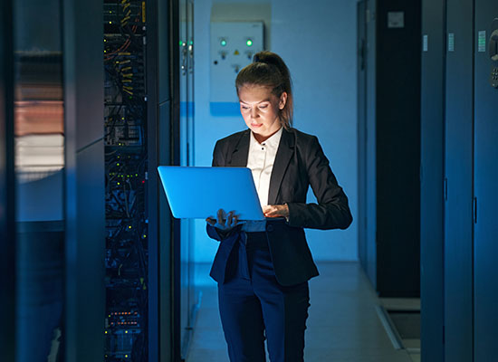 Women looking at laptop in computer server room